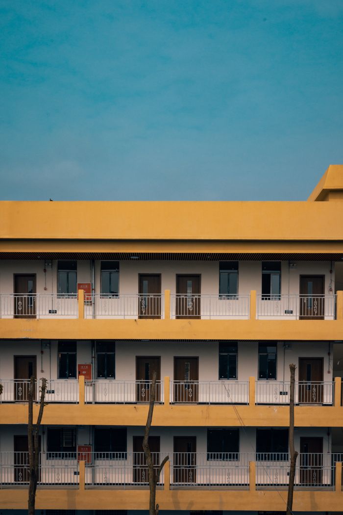 A yellow urban building facade featuring balconies and a vibrant clear sky.